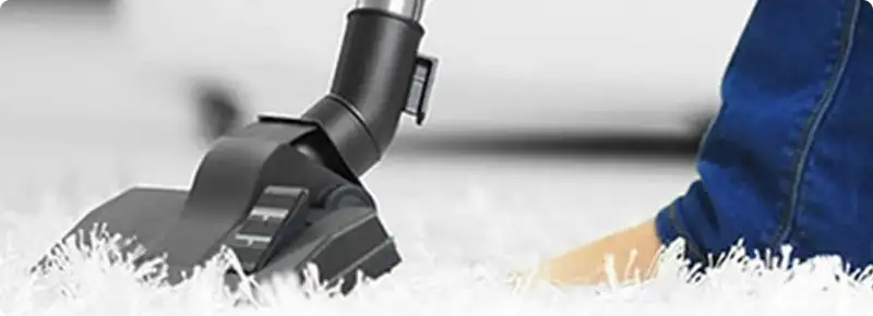 Close-up of a professional vacuuming a white carpet in Highland Park.